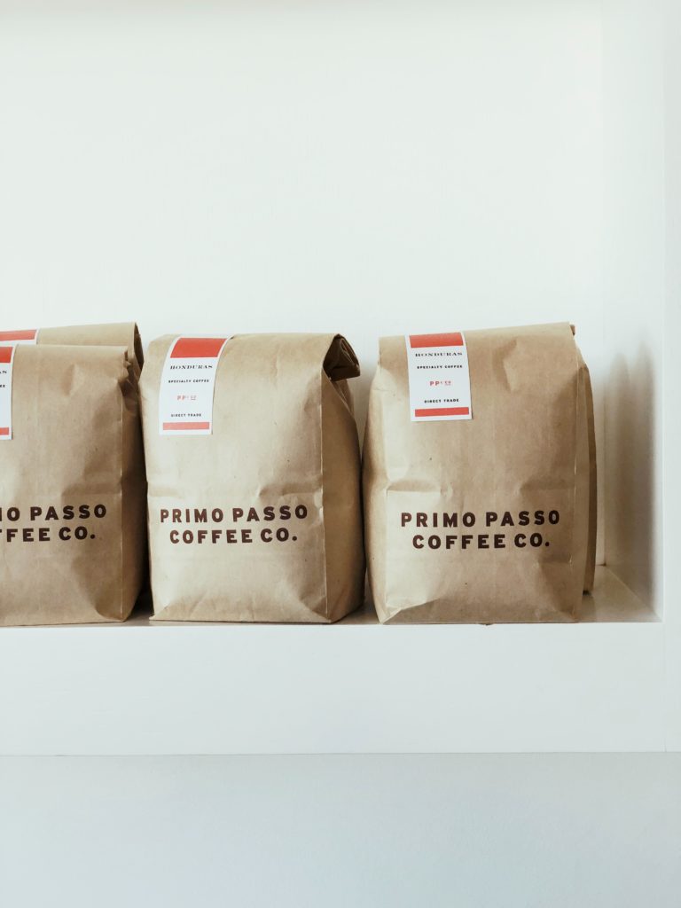 Three custom paper bags printed with Primo Passo Coffee Co. brand name.