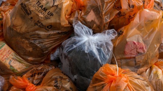 Plastic bags that are tightly closed with different types of garbage inside piled in one place.
